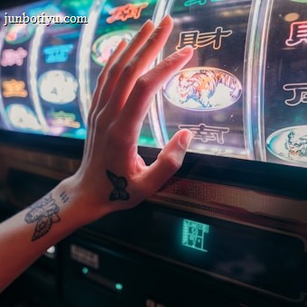 A hand with tattoos reaches towards a brightly lit slot machine, featuring various colorful symbols including a tiger. The image captures the moment of anticipation as the person engages with the machine during a game of chance.